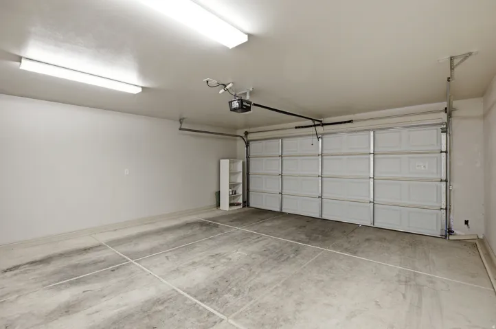 Spacious garage featuring a concrete floor, two fluorescent light fixtures, and an automatic garage door opener