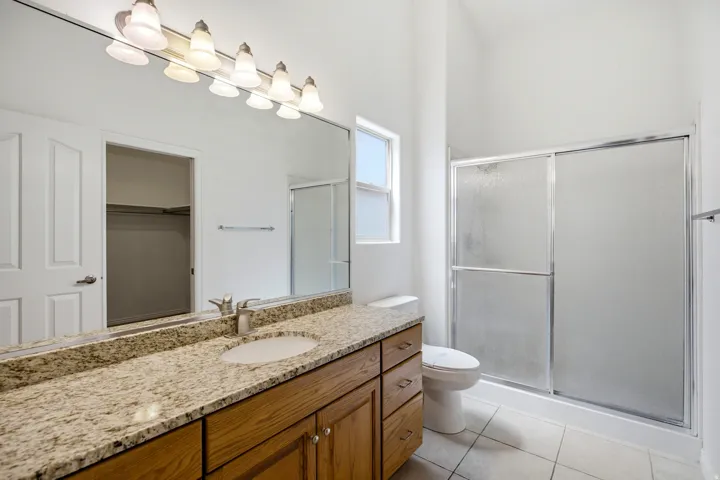 Bathroom featuring a wood-finish vanity with granite countertop, integrated sink, and chrome faucet