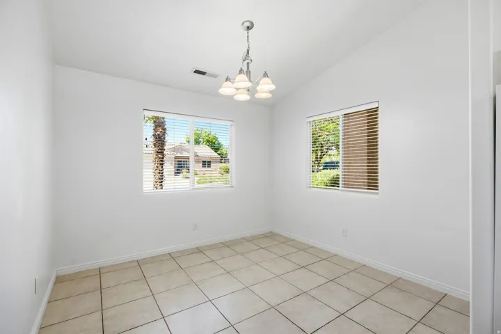 Room featuring light-toned square tile flooring, white walls, and a vaulted ceiling
