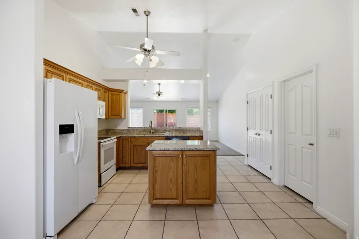 Kitchen featuring light wood cabinetry, granite-finish countertops, tile flooring, and a central island