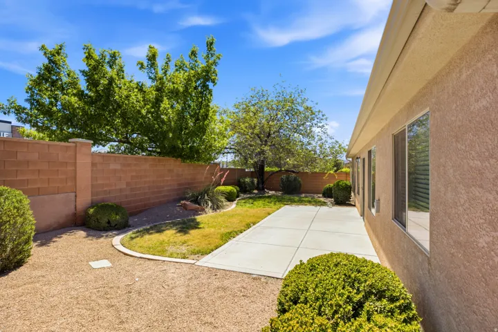Private backyard featuring a concrete patio, a section of turf, and gravel landscaping