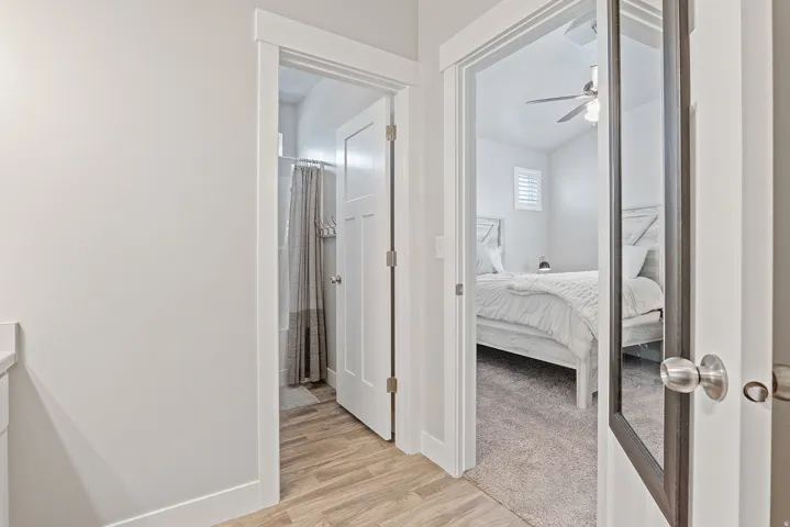 Interior corridor with light wood-finish flooring, white trim, and white paneled doors