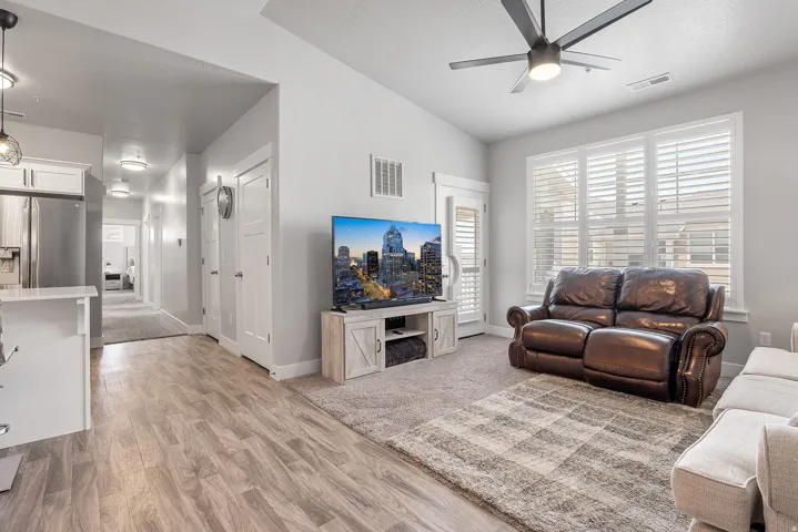 Spacious living area featuring vaulted ceilings, wood-finish flooring, and a contemporary ceiling fan