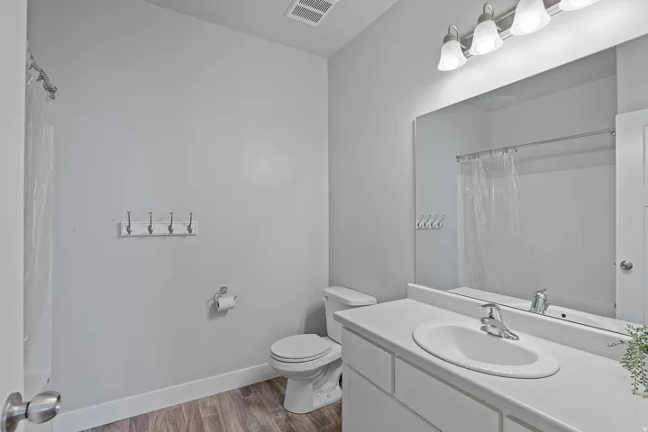 Bathroom featuring a vanity with an integrated sink, a rectangular mirror, and a wall-mounted light fixture