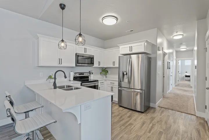 Contemporary kitchen featuring white cabinetry, stainless steel appliances, a white solid surface countertop, and wood-finish flooring