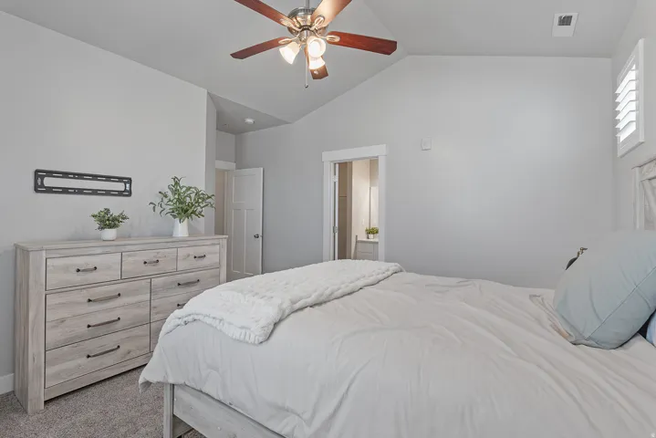 Vaulted ceiling with a ceiling fan, light gray wall paint, and white trim