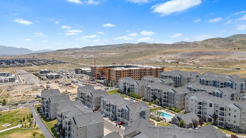 Aerial perspective showcasing a developing community with multi-story residential buildings, a central swimming pool, and surrounding green spaces