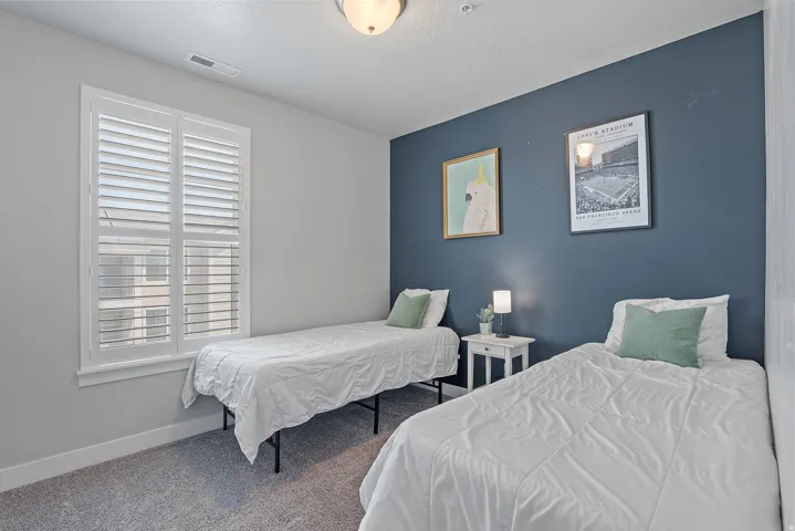 Room featuring carpeting, a painted accent wall, and a window with plantation shutters