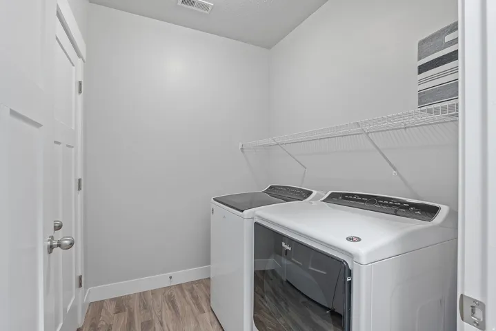 Dedicated laundry area featuring wire shelving, wood-finish flooring, and white trim