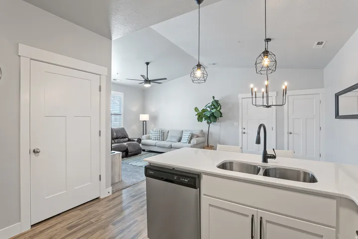 Kitchen island featuring a double basin stainless steel sink, black gooseneck faucet, and light-toned countertop