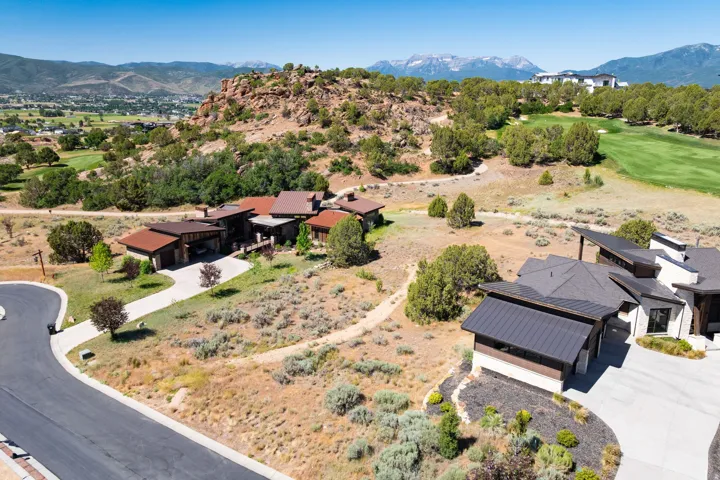 Mountainous backdrop with a golf course, paved driveway, and varied natural landscaping