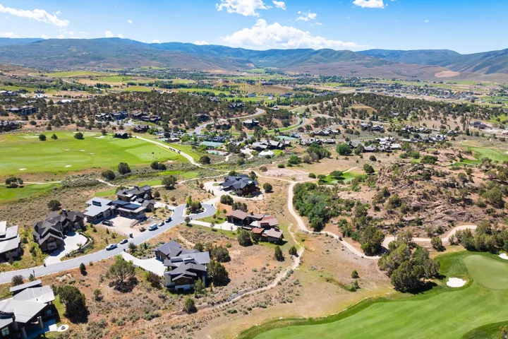 Mountainous terrain with residential properties, paved roads, and green golf course landscaping