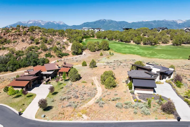 Expansive property featuring two distinct residences with concrete driveways, surrounded by natural desert landscaping