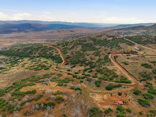 Expansive land parcel featuring natural terrain, scattered green shrubbery, and distant mountain ranges