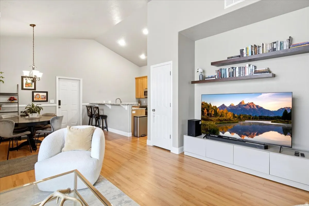 Open-concept living space featuring wood-finish flooring, vaulted ceilings, recessed lighting, and a dining area with pendant lighting