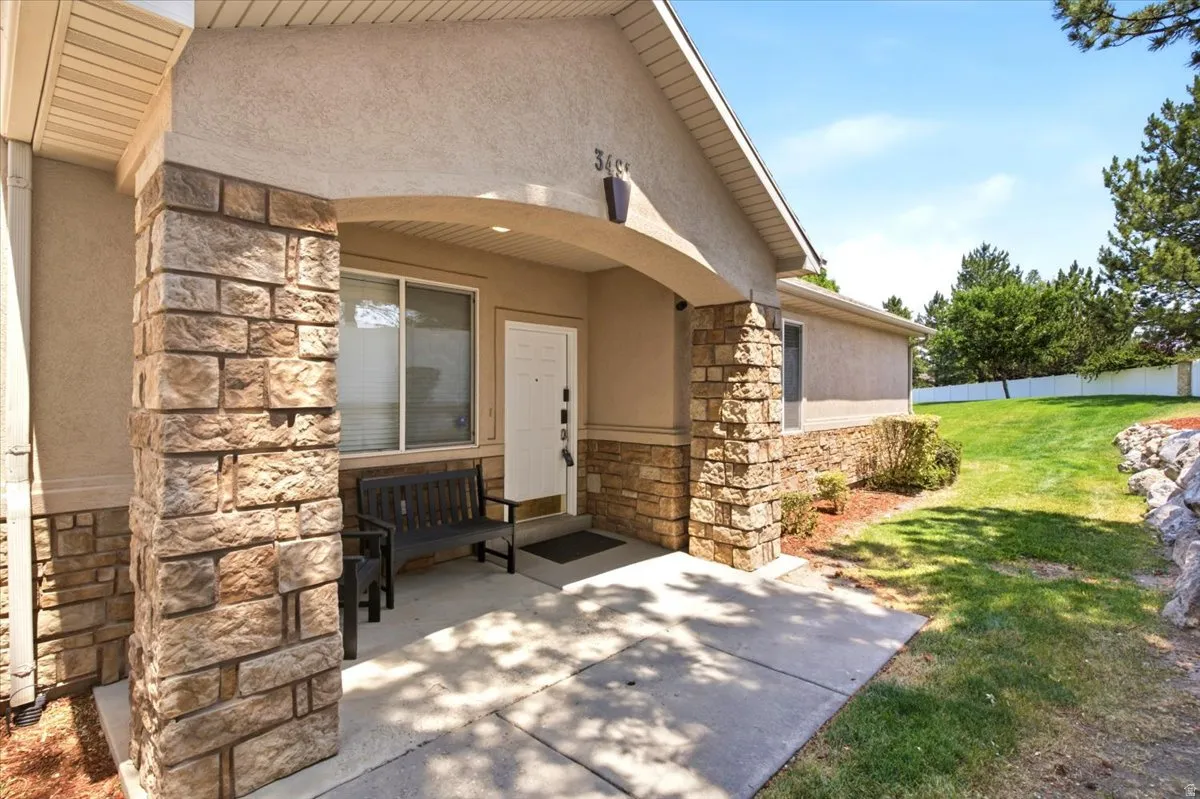 Covered entryway featuring stone veneer columns and stucco siding