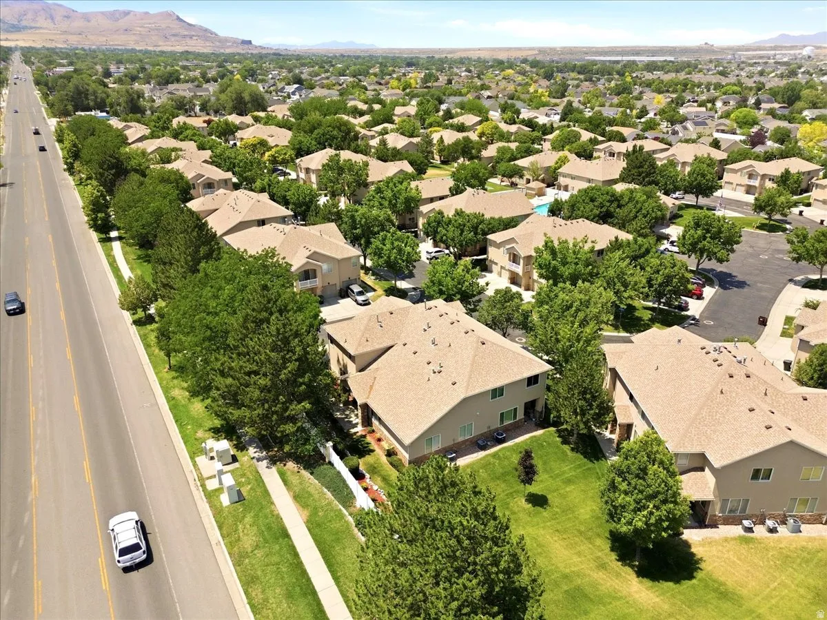 Aerial perspective showcasing a residential community with tree-lined streets, individual properties with pitched roofs, and a distant mountain range