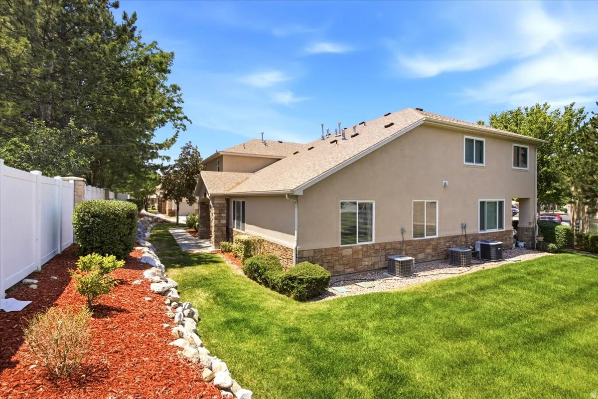 Exterior featuring a stucco finish with stone veneer accents, multiple windows, and a shingled roof