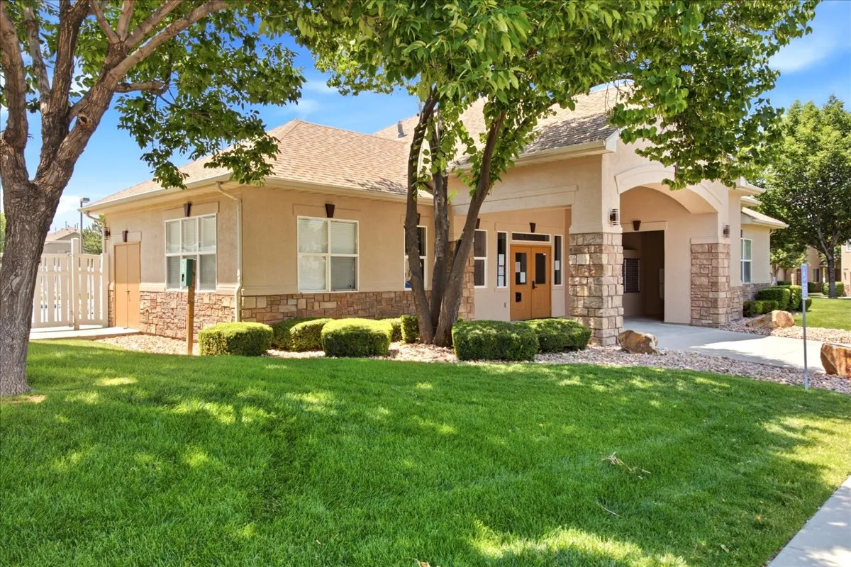 Exterior featuring a stucco finish with stone accents, a covered entry, multiple windows, and a manicured lawn