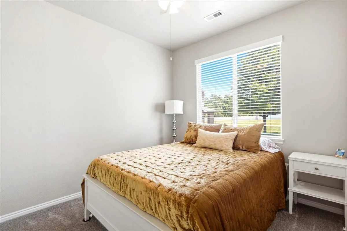 Light gray walls with white trim, a large window with white blinds, and gray carpeting