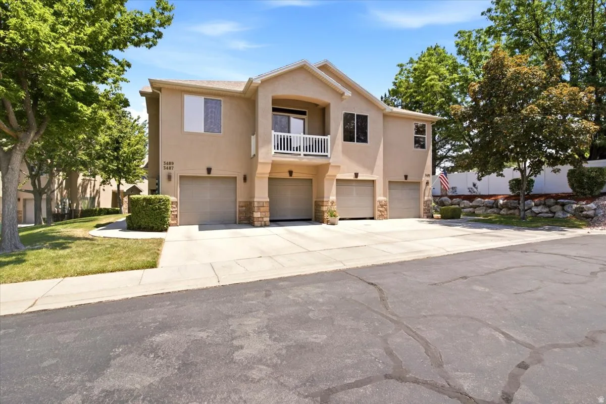 Multi-unit property featuring stucco exterior, individual garage access for each unit, and a private upper-level balcony with white railings