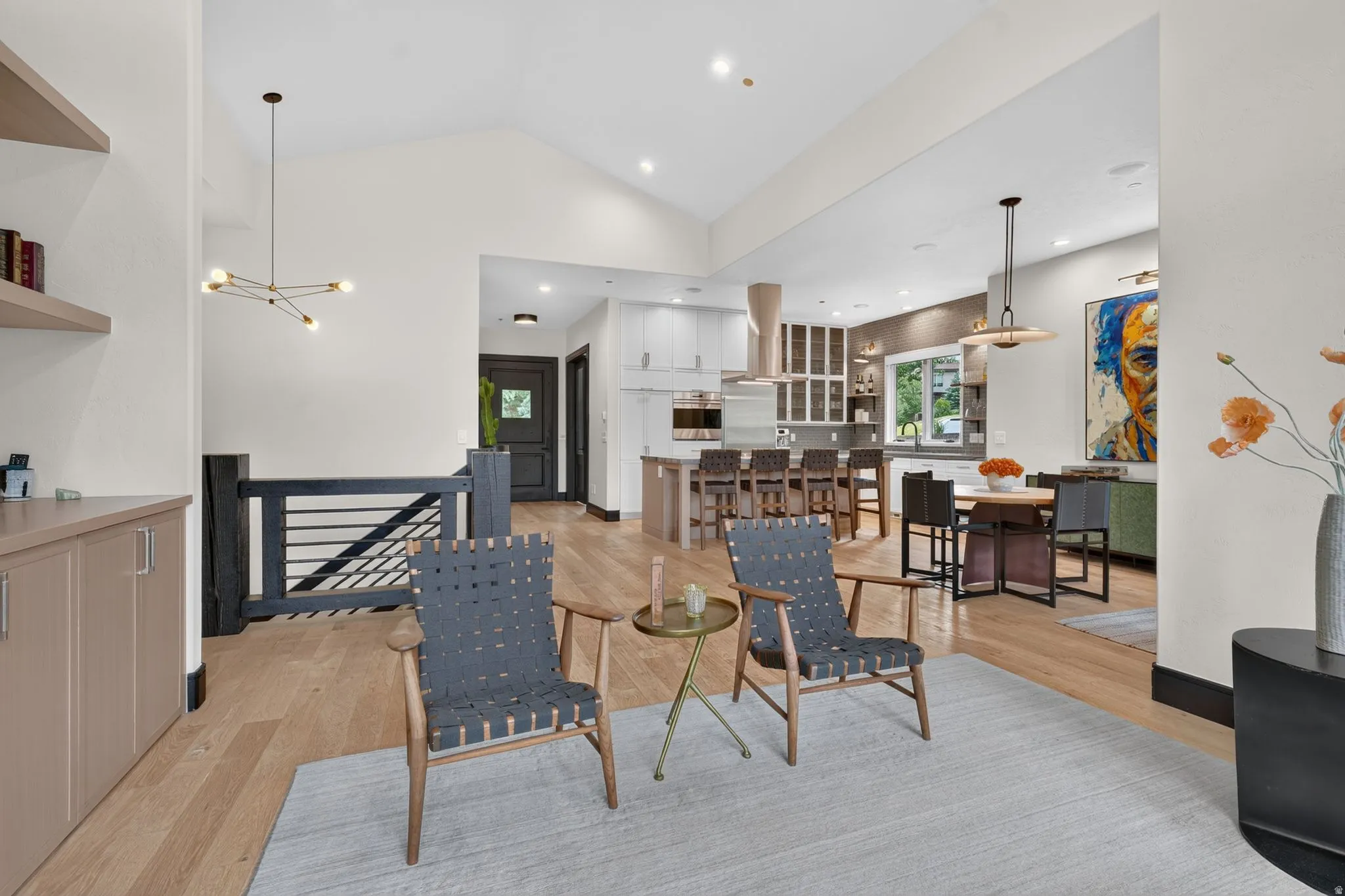 Open-concept living space featuring wood-finish flooring, vaulted ceilings, and a modern chandelier
