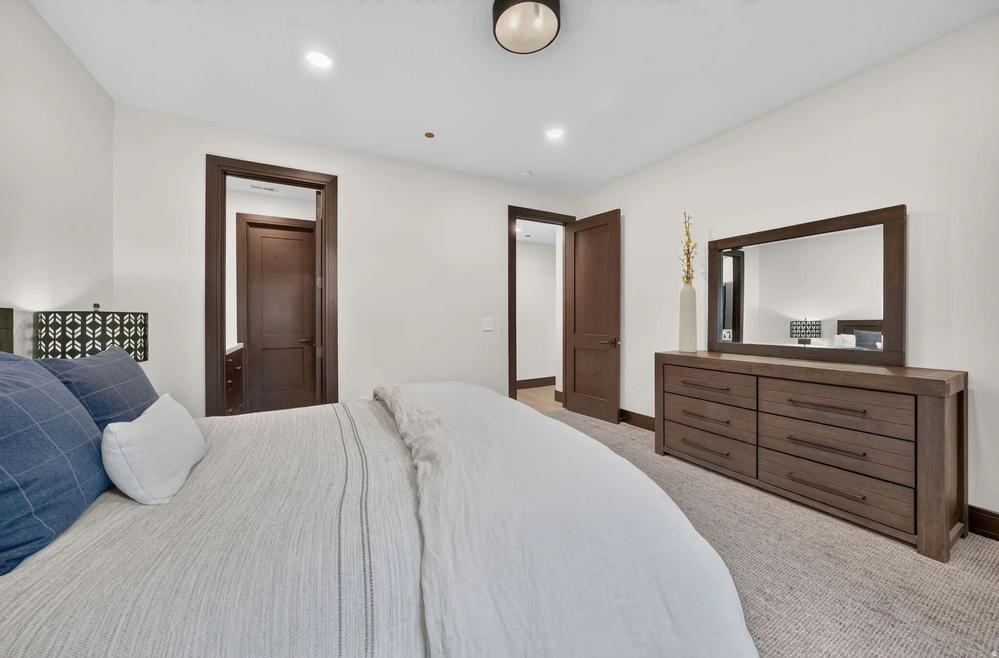 Carpeted bedroom featuring white walls, recessed lighting, and dark wood-finish trim and doors