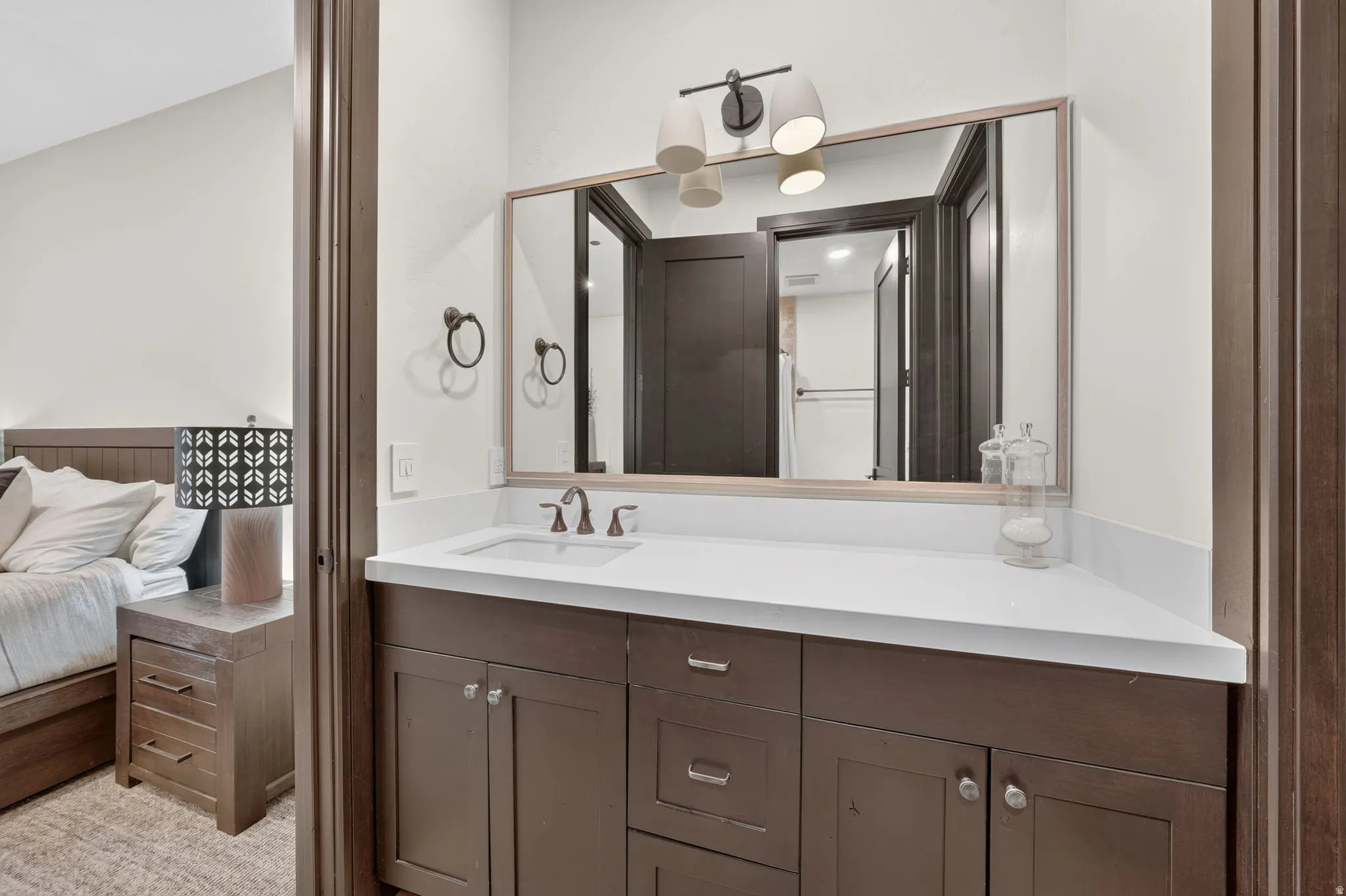 Bathroom vanity featuring a single undermount sink, a white countertop, and dark wood cabinetry