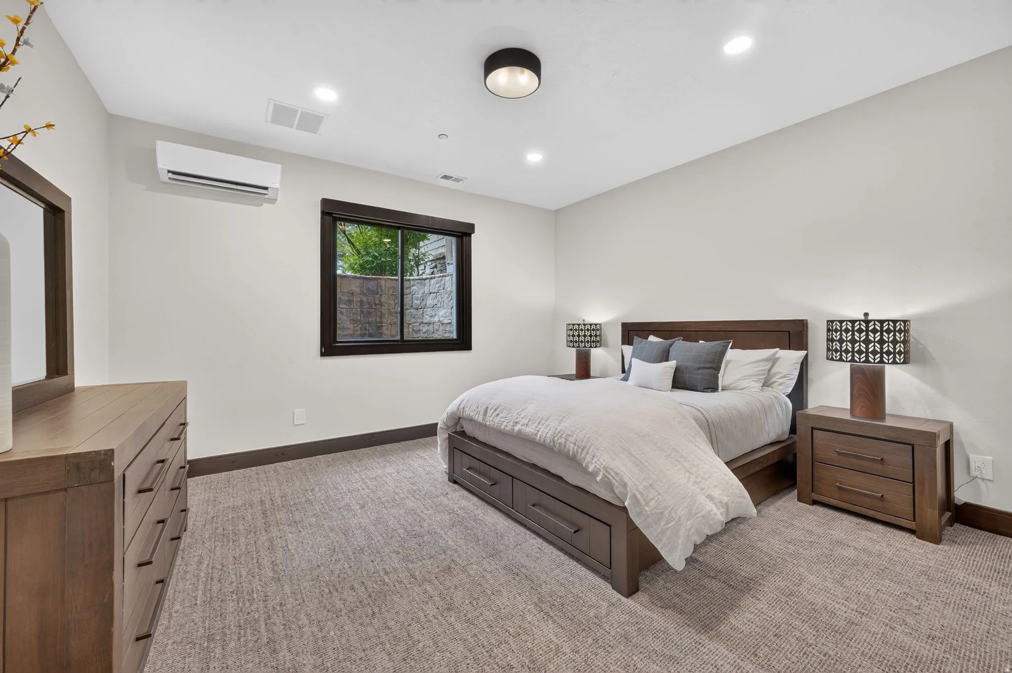 Carpeted bedroom featuring a dark wood window frame, recessed lighting, and a wall-mounted mini-split HVAC unit