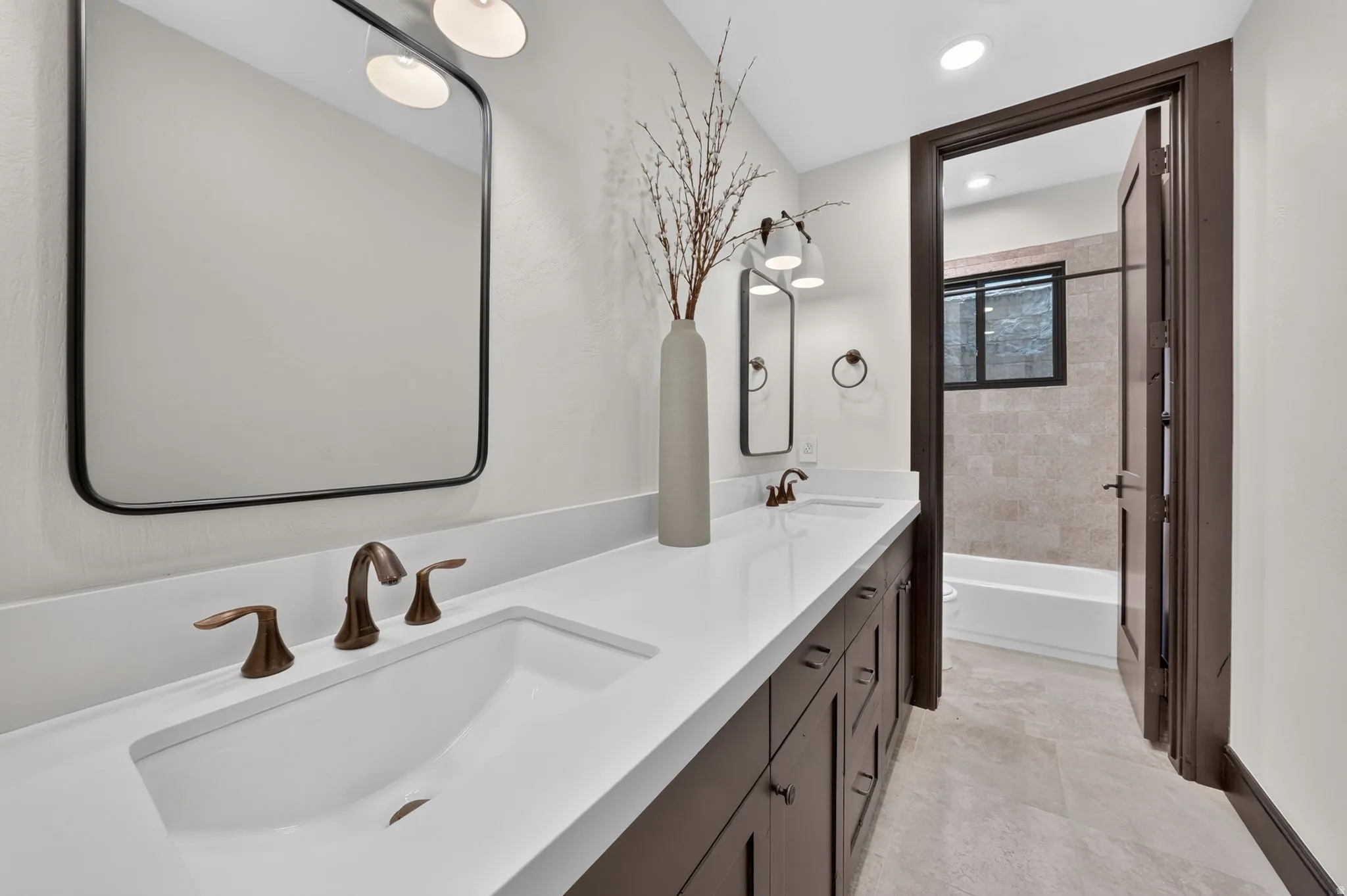 Bathroom featuring a dual vanity with integrated sinks, white countertops, and dark wood cabinetry