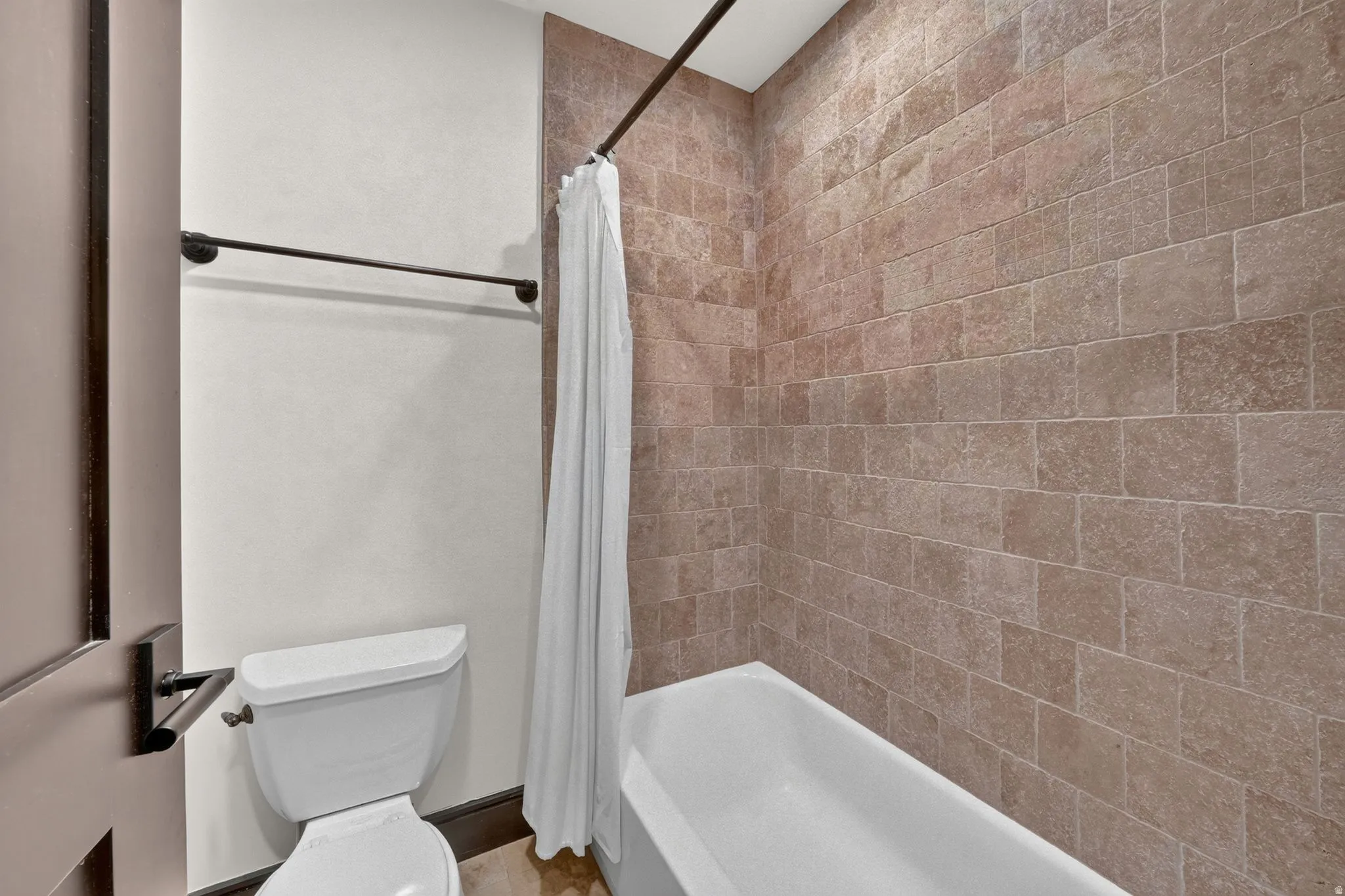 Bathroom featuring a white bathtub, subway tile shower surround, and a white toilet