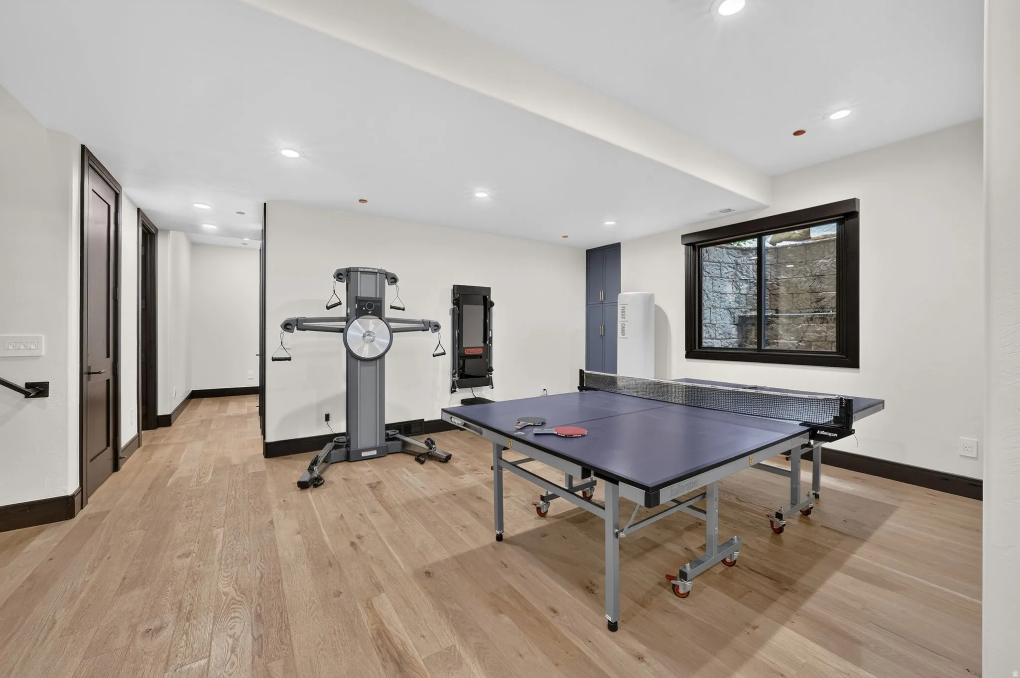 Spacious room featuring wood-finish flooring, recessed lighting, and dark trim