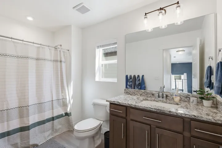 Contemporary bathroom featuring a dark wood-finish vanity with a granite-style countertop, undermount sink, and brushed nickel fixtures