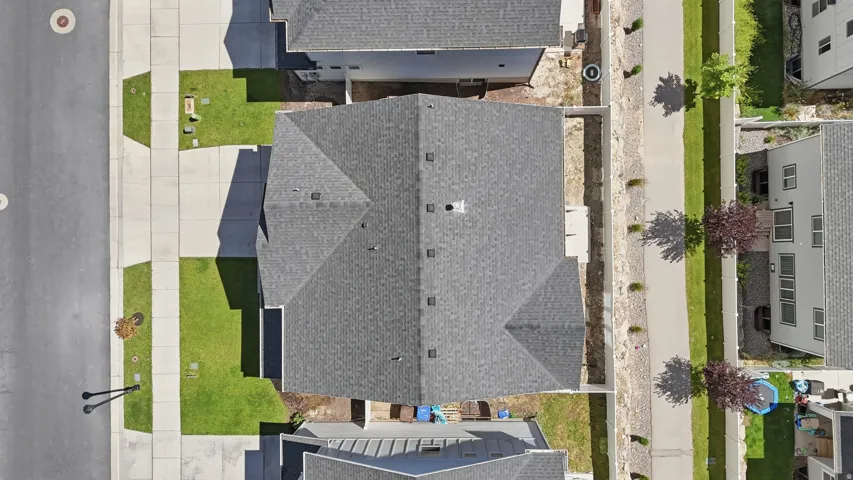 Gabled roofline property featuring dark gray shingles, a light gray concrete driveway, and a manicured green lawn