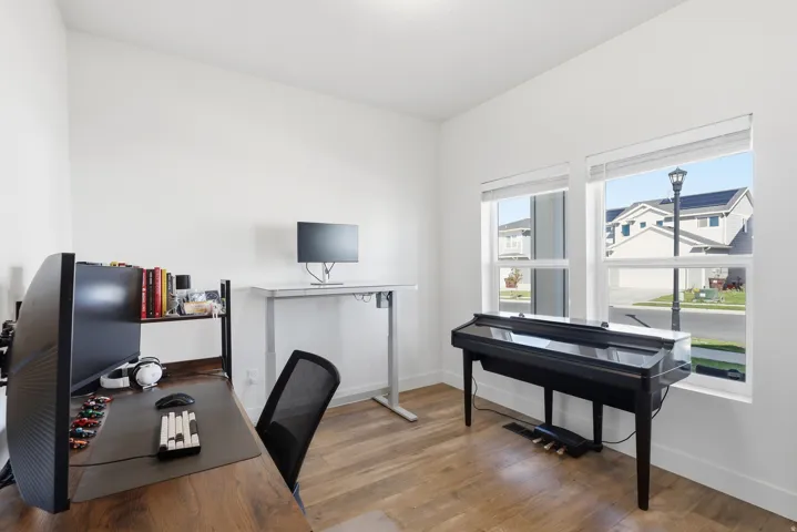 Bright interior space featuring wood-finish flooring, white walls, and two large windows with white blinds