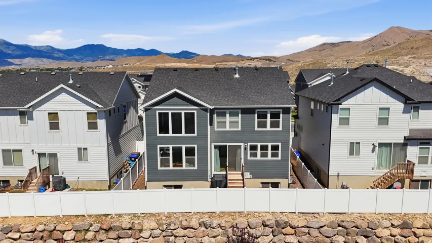Modern gray siding exterior with multiple windows, a rear deck, and a sliding glass door