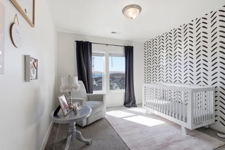 Bright room featuring a patterned accent wall, light-toned carpeting, and a window with dark curtains