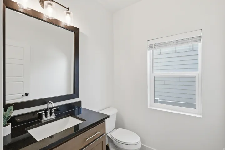 Vanity with dark granite countertop, undermount sink, and brushed nickel faucet
