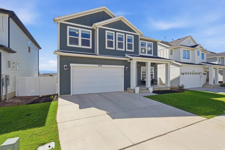 Contemporary two-story residence featuring a dark blue exterior with white trim, an attached two-car garage, covered porch entry, and a paved driveway