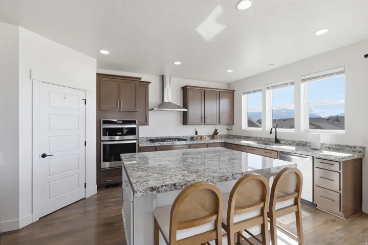 Kitchen featuring a large central island with a light-toned countertop, recessed ceiling lighting, and wood-finish flooring