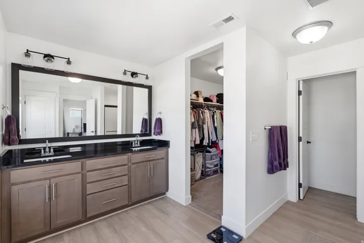 Double vanity with dual sinks, dark countertop, and wood-finish cabinetry