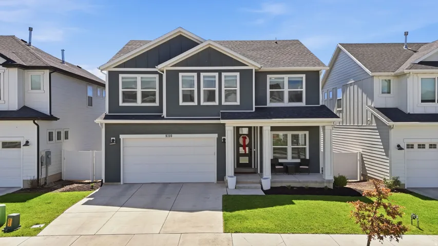 Contemporary two-story residence featuring a dark gray facade with white trim accents and a covered front porch