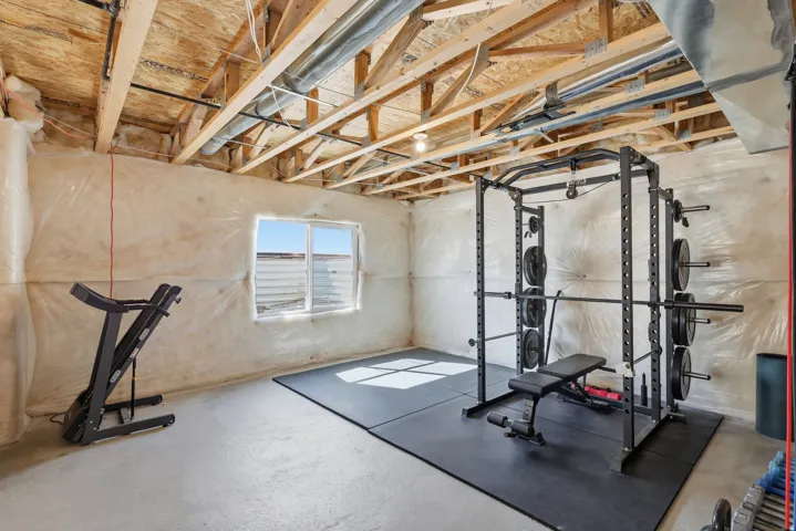 Lower level space featuring exposed ceiling joists, concrete flooring, a window, and insulated wall framing