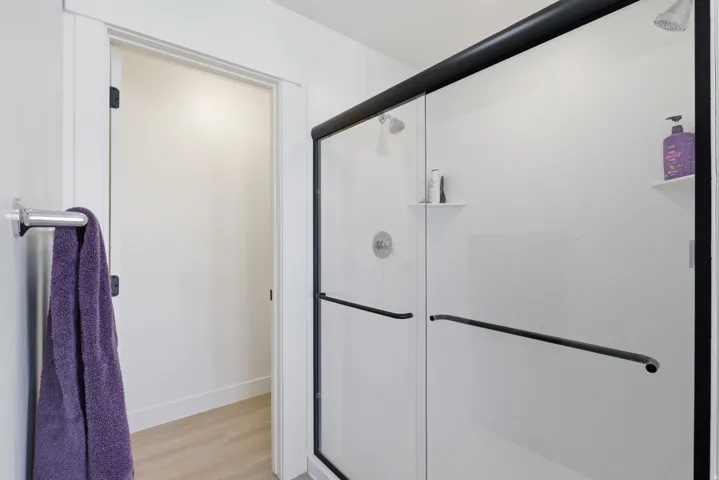 Enclosed shower with clear glass sliding door featuring matte black framing and hardware