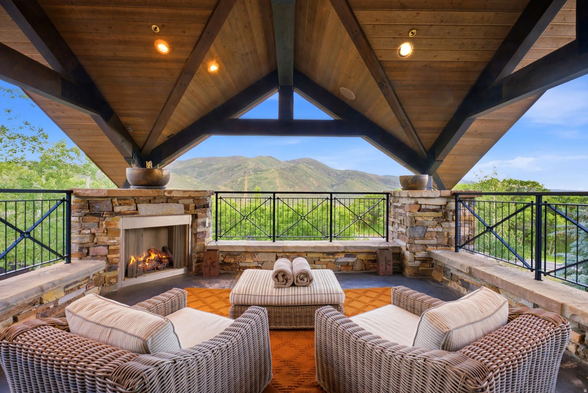 Covered outdoor patio featuring a stone-clad fireplace and wood-plank vaulted ceiling