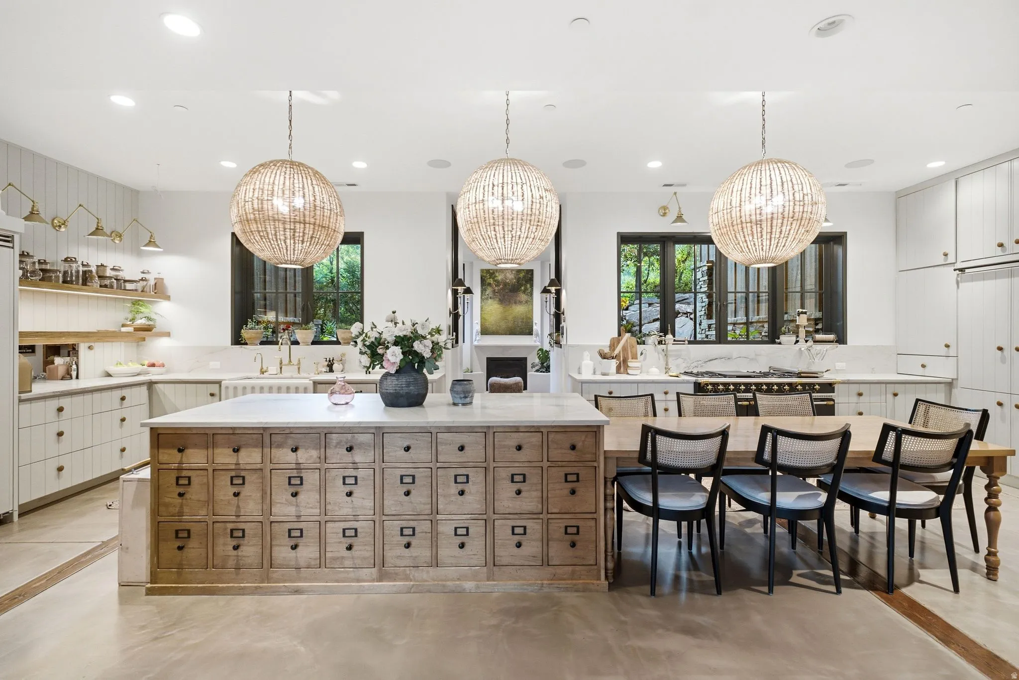 Kitchen featuring an oversized island with extensive drawer storage, integrated dining table, and three large pendant lights