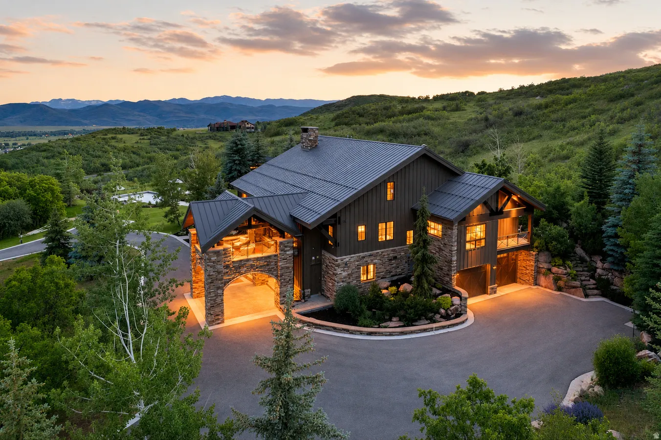 Mountain contemporary residence featuring a stone and board-and-batten exterior, dark metal roof, and an arched porte-cochère