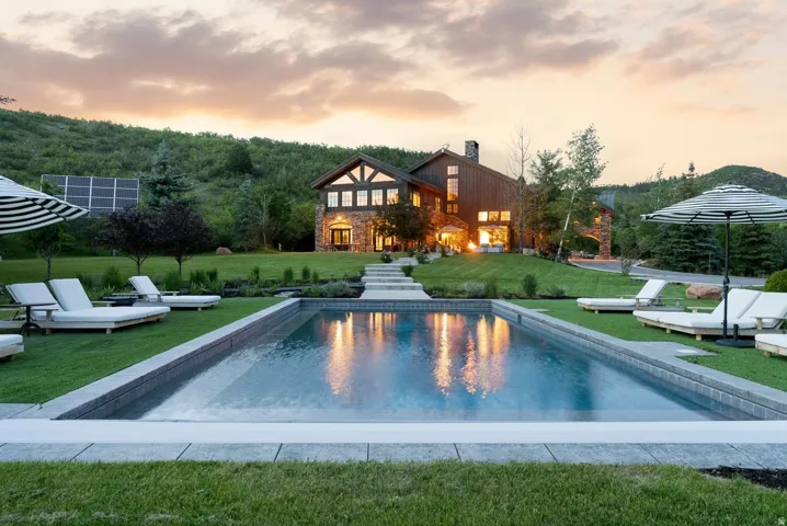 Rectangular swimming pool with stone coping surrounded by manicured lawn