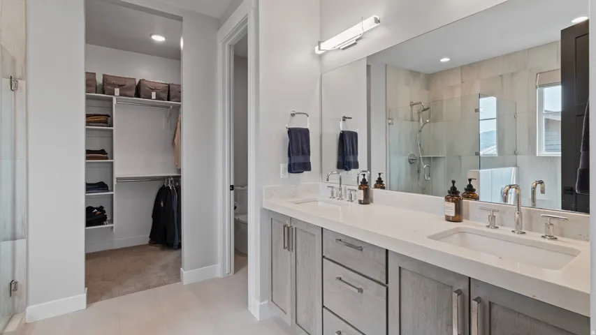 Primary suite's bathroom, featuring double vanity with integrated sinks, is light and airy with high ceilings and incredible views out the windows.