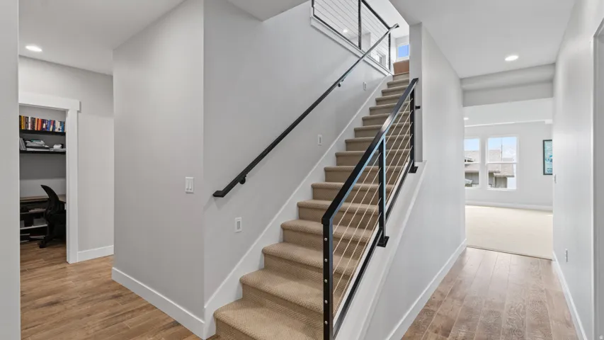 Modern staircase with cable railing, carpeted treads, and wood-finish flooring brings you to the lower level where you will find the Pocket Office (to the left) and the large lower family/game room with lots of light and big views.  There are also two bed